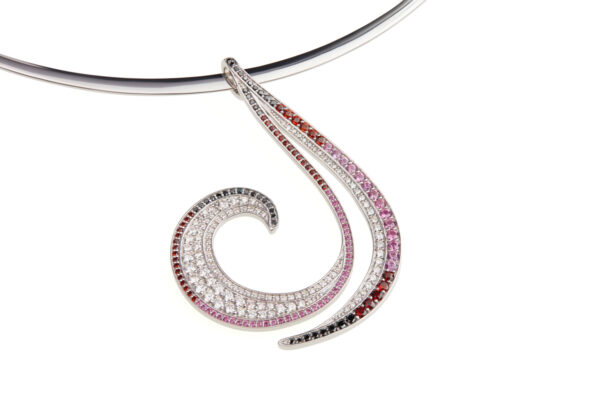 19k white gold pendant that is narrow at the top and broadens into a spiral shape. The spiral begins with red garnets, transitions into merlot garnets, pink sapphires, white diamonds, and black diamonds at the tapered end.